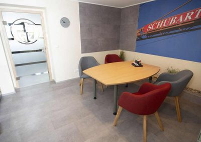 Ein modern eingerichteter Besprechungsraum mit einem runden Tisch und Stühlen auf einem DISANO-Designboden in Betonoptik.