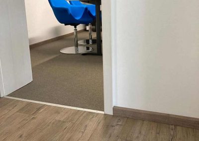 Der Übergang zwischen einem eleganten Vinylboden und einem modernen Teppichboden in einem stilvollen Raum.